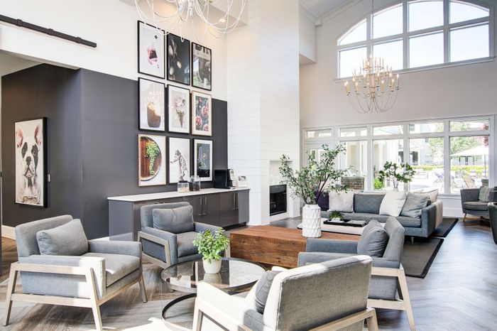 Elegant living area featuring modern gray furniture, vibrant artwork, and large windows with natural light.