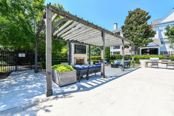Chic outdoor lounge area featuring a stylish pergola, cozy seating, and a modern fireplace, ideal for relaxation and entertainment.