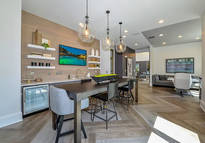 Chic open-concept living space featuring a stylish dining area with modern pendant lights, a sleek built-in bar, and a cozy lounge with elegant decor.