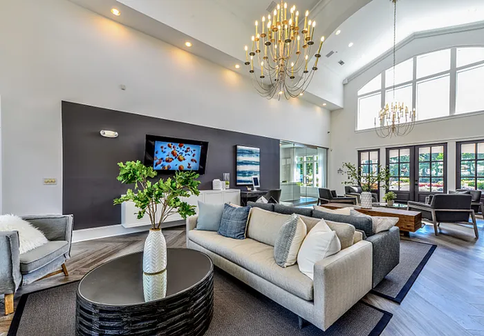 Luxurious living room with high ceilings, elegant chandeliers, modern sofas, and large windows offering natural light.