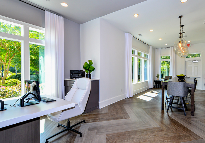 Bright and modern interior featuring a sleek office space with a desk and white chair, complemented by a spacious dining area and large windows overlooking a lush garden.
