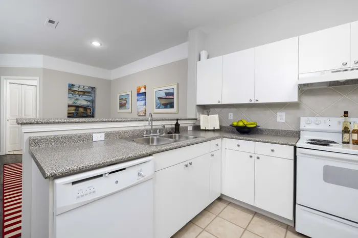 Modern kitchen featuring sleek white cabinetry, granite countertops, and stylish tile backsplash with contemporary art decor.