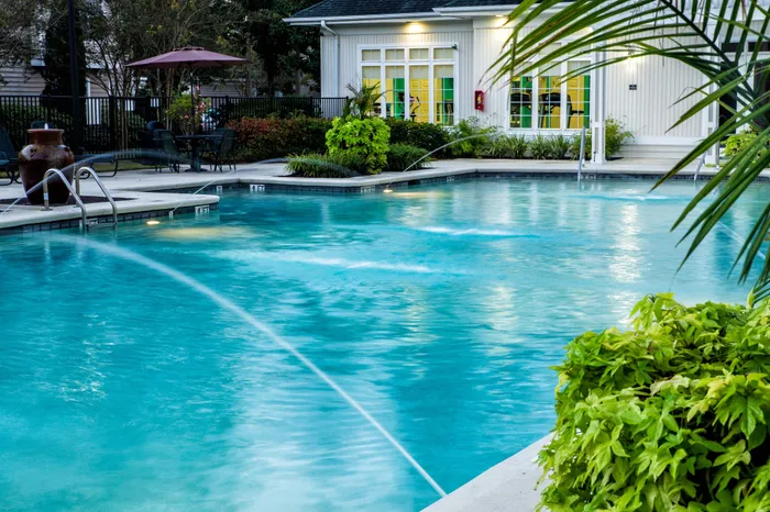Inviting outdoor pool area surrounded by lush greenery and elegant patio seating, perfect for relaxation and leisure.