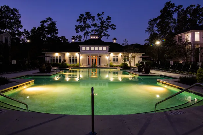 Luxurious swimming pool illuminated at dusk, framed by a charming clubhouse, inviting relaxation in a serene setting.