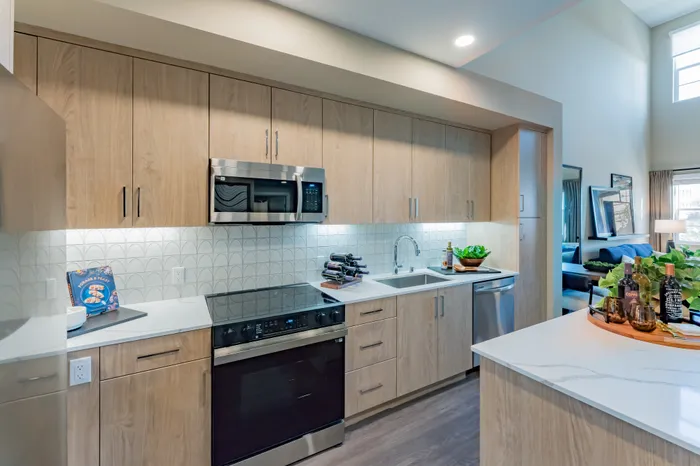Model living room and kitchen with stylish decor and open layout at Marlowe Palomar Heights new apartments in Escondido, CA.