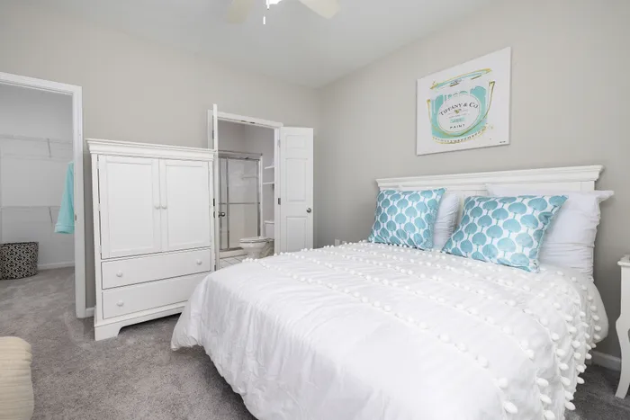Bright and inviting bedroom with elegant white furniture and cozy bedding, featuring calming blue accents and a spacious closet.