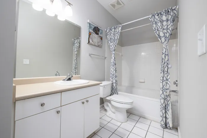 Bright and modern bathroom with elegant vanity and patterned shower curtain, creating a stylish and refreshing ambiance.