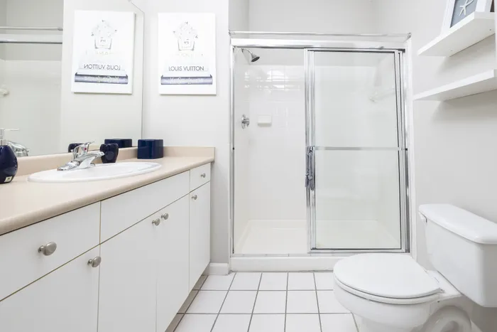 Bright and modern bathroom featuring a sleek countertop with dual sinks, a glass-enclosed shower, and elegant decor.