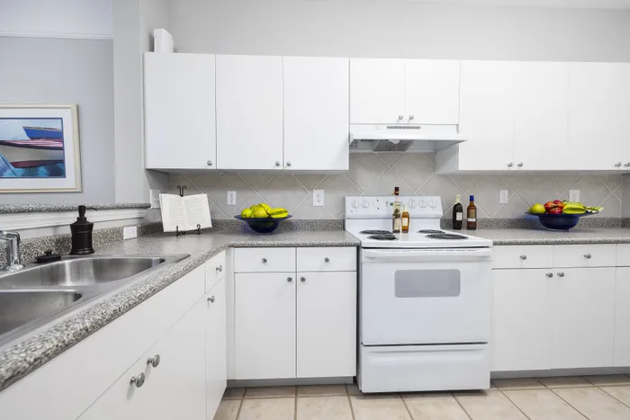 Bright and modern kitchen featuring sleek white cabinets, a polished countertop, and charming decor, perfect for culinary creativity and family gatherings.