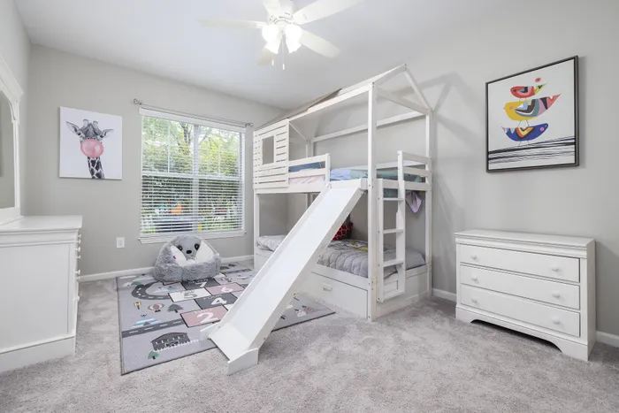 Charming children's bedroom with playful bunk bed and slide, cozy reading nook, and modern decor.