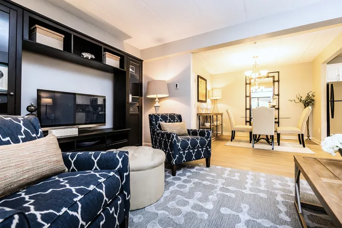 Inviting living and dining area with stylish decor, featuring patterned armchairs, modern lighting, and a sleek entertainment center for a cozy atmosphere.