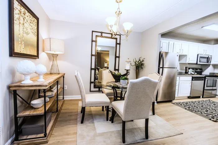 Inviting dining area with elegant chandelier, paired with a modern kitchen featuring stainless steel appliances and stylish decor.
