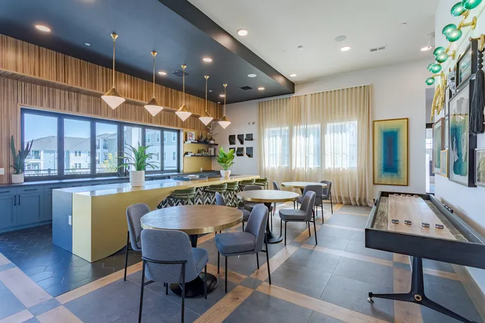 Chic and modern entertainment space with stylish lighting, elegant seating, and a sleek shuffleboard table, perfect for social gatherings.