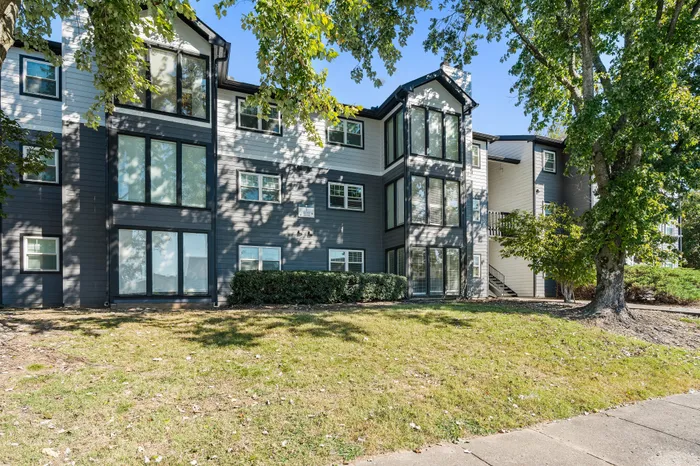 Charming modern apartment building with large windows and lush green surroundings, showcasing stylish architecture and inviting outdoor spaces.