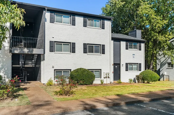 Charming apartment building with modern exterior, lush greenery, and inviting walkway in a serene neighborhood.