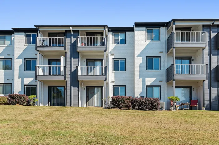 Modern apartment building with spacious balconies, elegant facade, and well-maintained green lawn, perfect for comfortable living.
