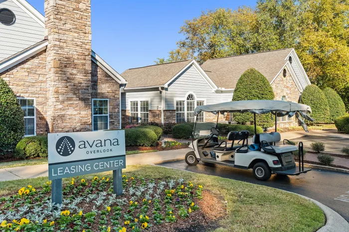 Charming leasing center at Avana Overlook with a welcoming facade, vibrant landscaping, and convenient golf cart ready for tours.