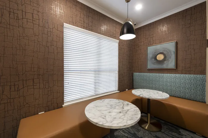 Chic dining nook with modern marble tables, cozy seating, and artistic wall decor.