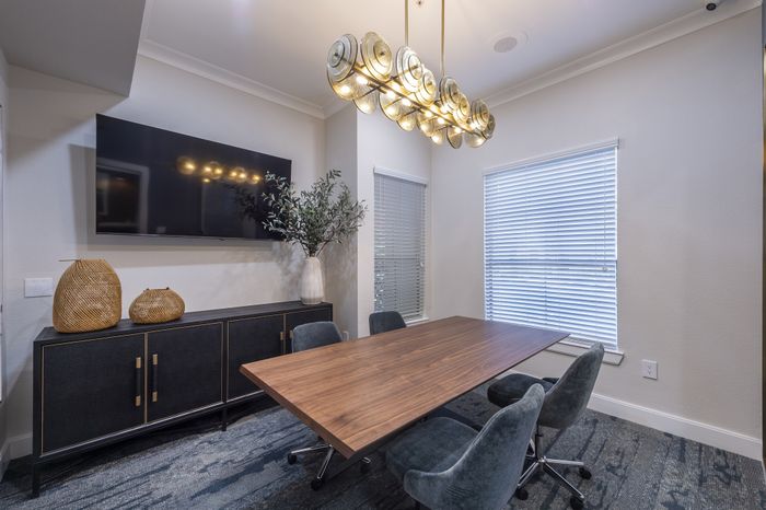 Elegant dining area with a modern wooden table, stylish grey chairs, and a unique chandelier, creating a sophisticated ambiance.