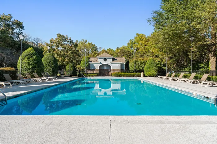 Inviting outdoor pool surrounded by lush greenery and comfortable lounge chairs, perfect for relaxation and leisure.
