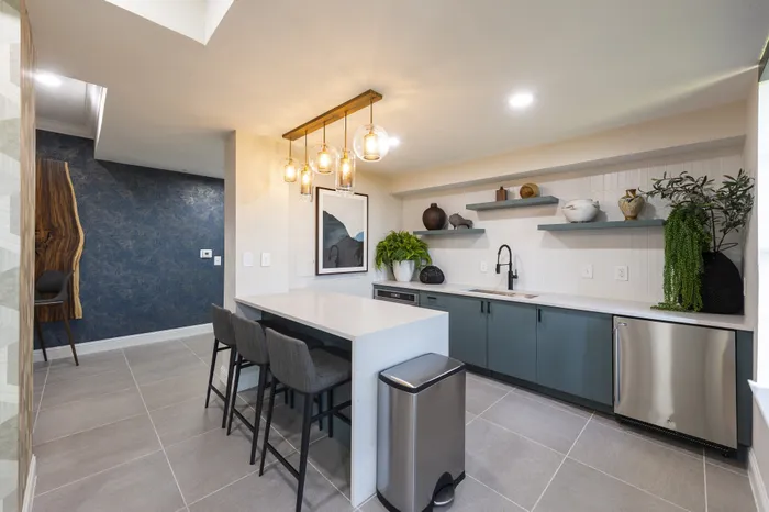 Modern kitchen with sleek countertops, elegant pendant lighting, and stylish cabinetry, featuring a chic open layout and contemporary art.