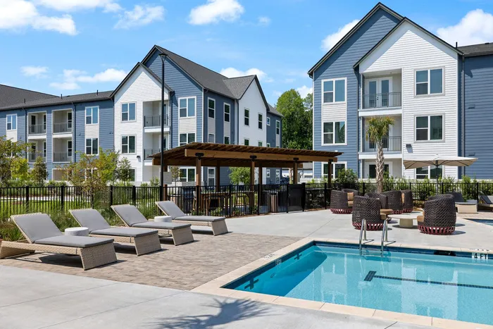 Pool courtyard with chaise loungers and a pergola with outdoor kitchen