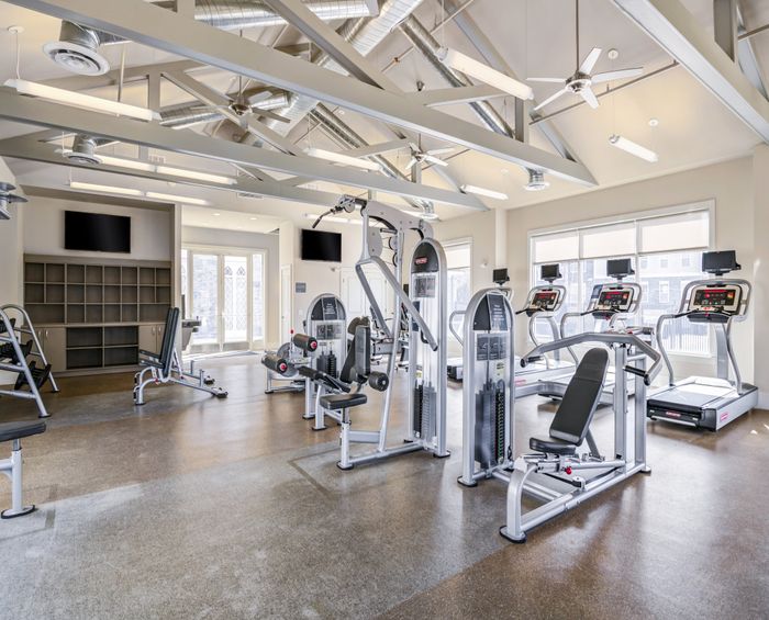 Modern fitness center featuring state-of-the-art gym equipment, including treadmills and weight machines, with bright natural lighting and sleek architectural design.