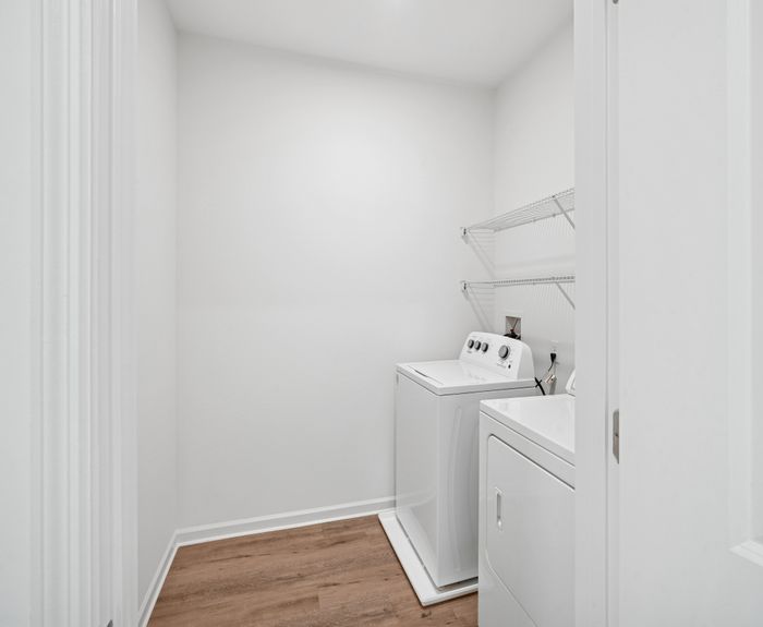 Modern laundry room with sleek washer and dryer, featuring elegant wooden flooring and ample shelving space.