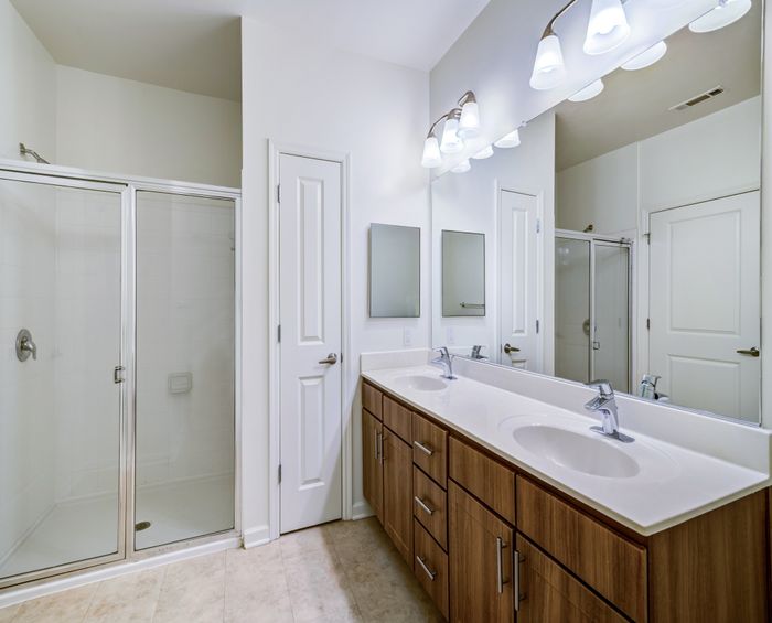 Elegant bathroom with dual sinks, wooden cabinetry, and a spacious glass-enclosed shower.
