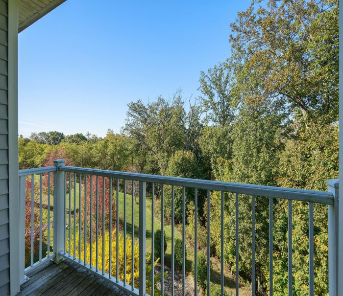 Serene apartment balcony view overlooking lush green trees and a clear blue sky, perfect for relaxation.