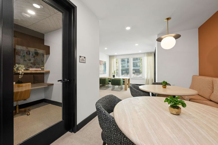 Contemporary co-working lounge interior with cozy seating area, modern workspace, and large windows inviting natural light.