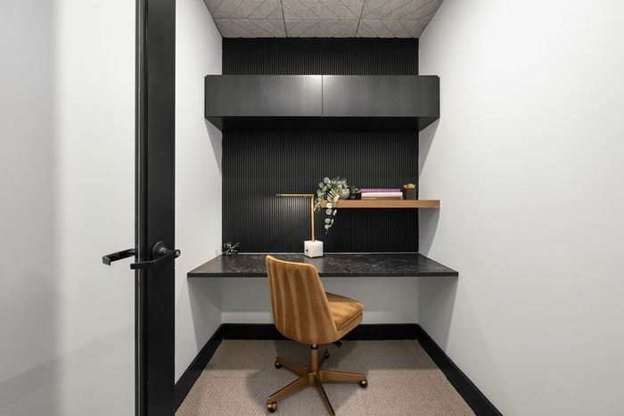 Chic conference call office nook with a sleek black desk, stylish chair, and modern shelving for a productive workspace.
