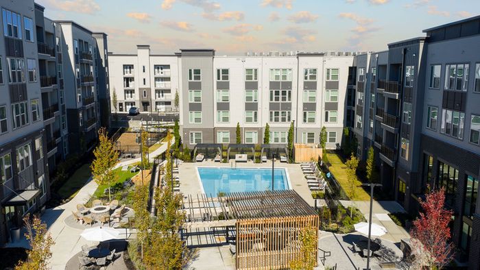 Charming apartment courtyard with a sparkling pool, surrounded by modern buildings and lush landscaping.