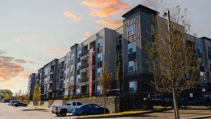 Modern apartment complex with sleek architecture, spacious balconies, and vibrant sunset, now leasing.