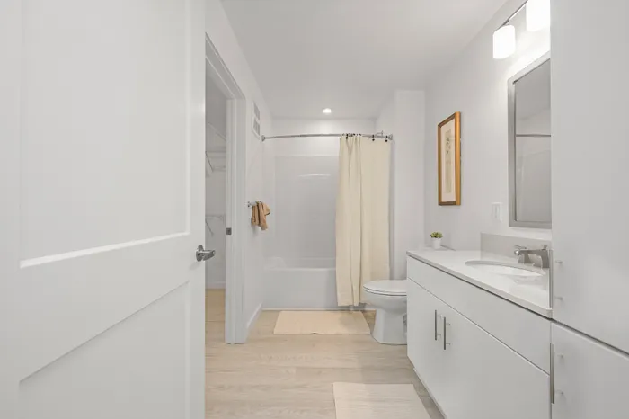 Bright and modern bathroom with sleek white vanity, elegant lighting, and inviting bathtub, offering a tranquil retreat.