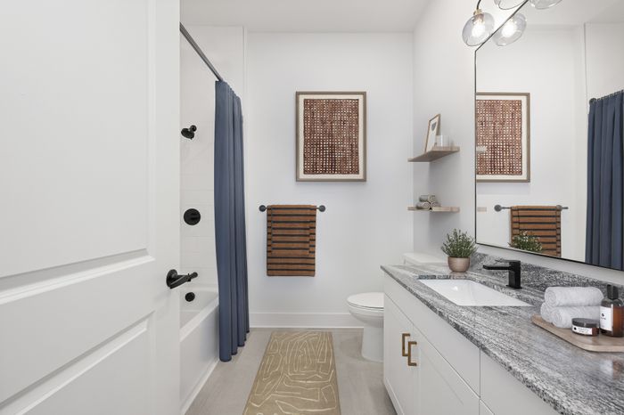 Contemporary bathroom with elegant granite countertop, stylish decor, and inviting bathtub with dark fixtures.