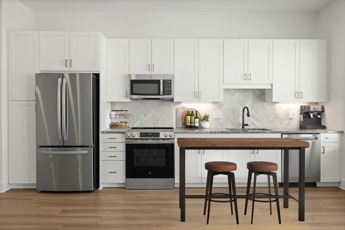 Modern kitchen with elegant white cabinetry, sleek stainless steel appliances, and a stylish island with bar stools.