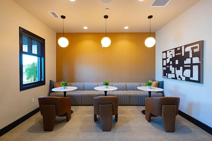 Chic seating area with elegant lighting, contemporary art, and cozy armchairs perfect for a stylish apartment ambiance.