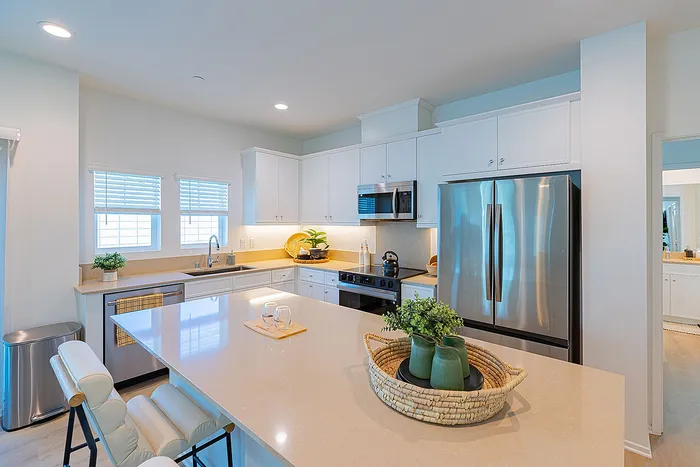 Modern kitchen with sleek cabinetry, stainless steel appliances, and a spacious island featuring elegant lighting.