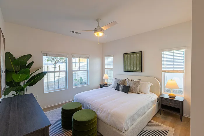 Bright and inviting bedroom with modern decor, featuring a large comfortable bed, stylish nightstands with lamps, and lush green plants by the window.