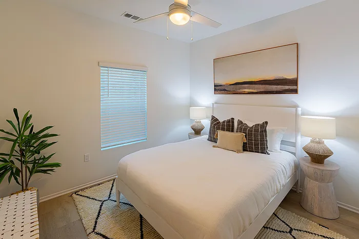 Cozy bedroom with elegant lighting, featuring a plush bed with stylish pillows, modern artwork, and an inviting atmosphere.