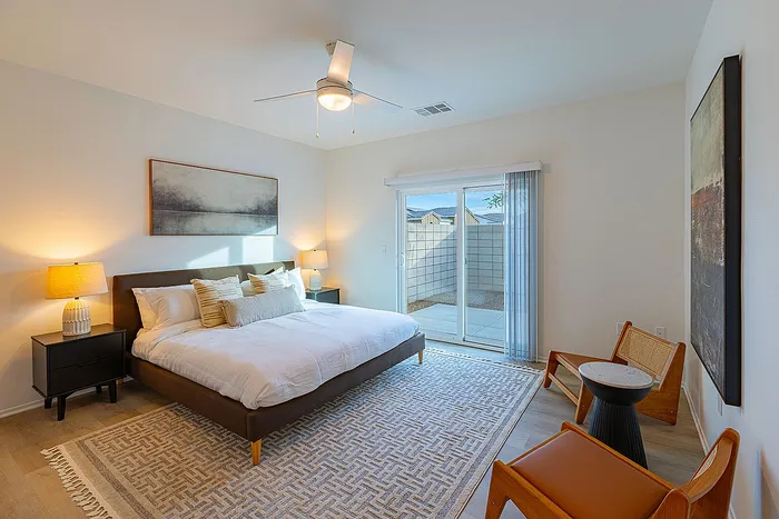 Inviting bedroom with modern decor, featuring a large window for natural light, elegant furnishings, and a cozy atmosphere.