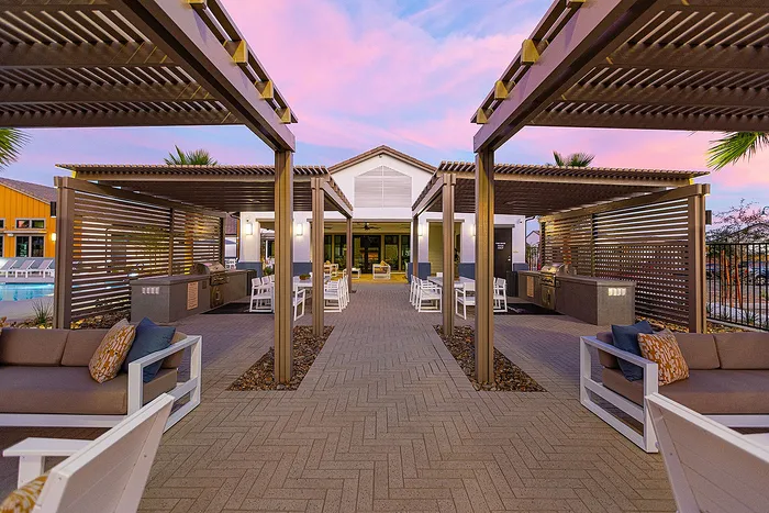 Elegant outdoor lounge area with modern pergolas, cozy seating, and vibrant sunset sky, perfect for relaxation and social gatherings.