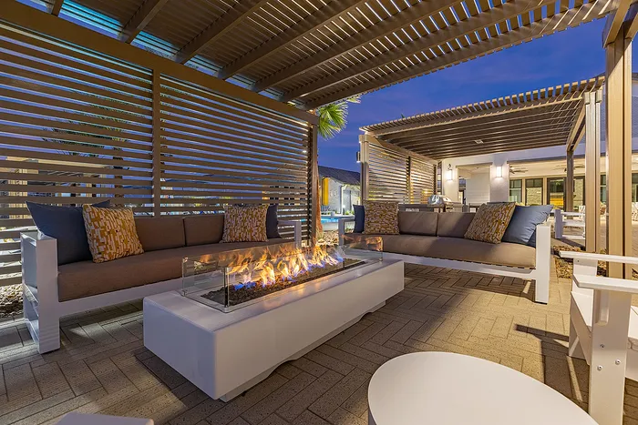 Inviting outdoor lounge area with modern fire pit, stylish seating, and ambient evening lighting.