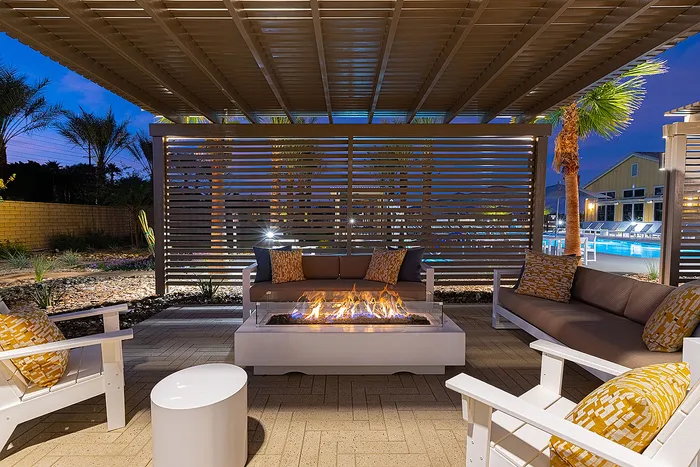 Elegant outdoor lounge area with cozy seating around a modern fire pit, overlooking a sparkling pool under a stylish pergola.