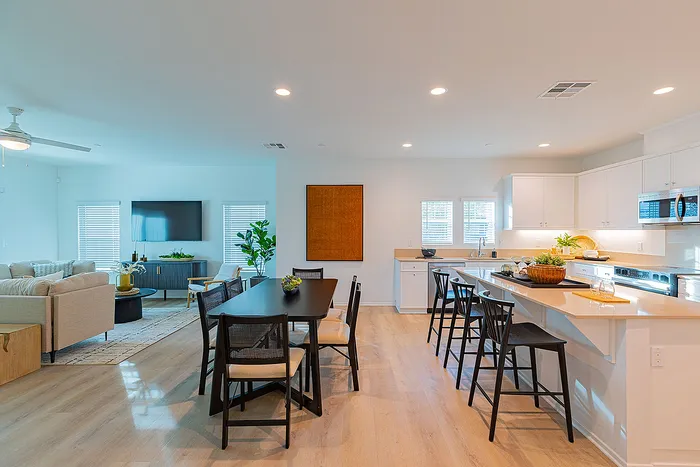 Bright and spacious open-concept living and dining area featuring modern kitchen, elegant dining table, and cozy living room with stylish furnishings.