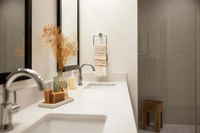 Modern bathroom with sleek fixtures, dual mirrors, elegant decor, and a stylish tiled shower.