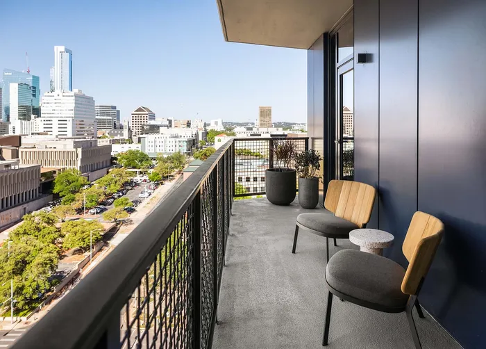 Modern balcony with chic seating overlooking a vibrant cityscape, perfect for urban living.