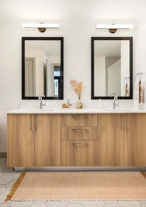 Elegant modern bathroom with dual wooden vanities, sleek mirrors, and soft lighting, creating a luxurious and serene atmosphere.