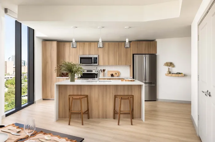 Modern kitchen with a stylish wooden island, sleek appliances, and expansive windows providing city views.